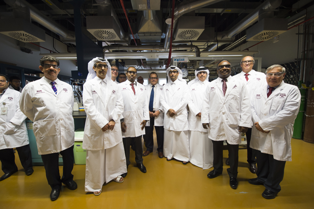 Group of men with white lab coats in a lab.